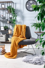 Comfortable armchair with blanket and houseplants in room