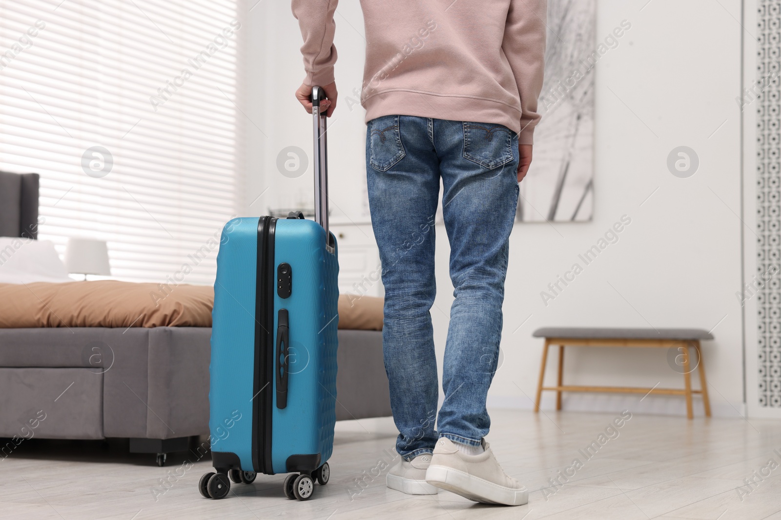 Photo of Guest with suitcase walking in hotel room, closeup