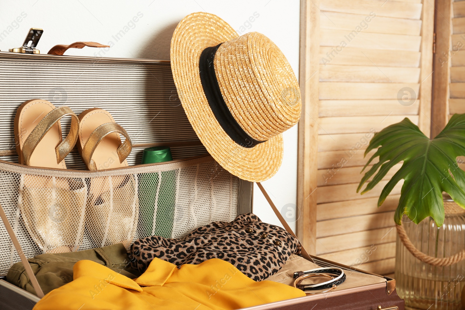 Photo of Vintage suitcase with clothes and shoes indoors, closeup