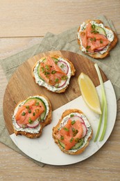 Photo of Tasty canapes with salmon served on wooden table, top view
