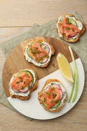 Tasty canapes with salmon served on wooden table, top view