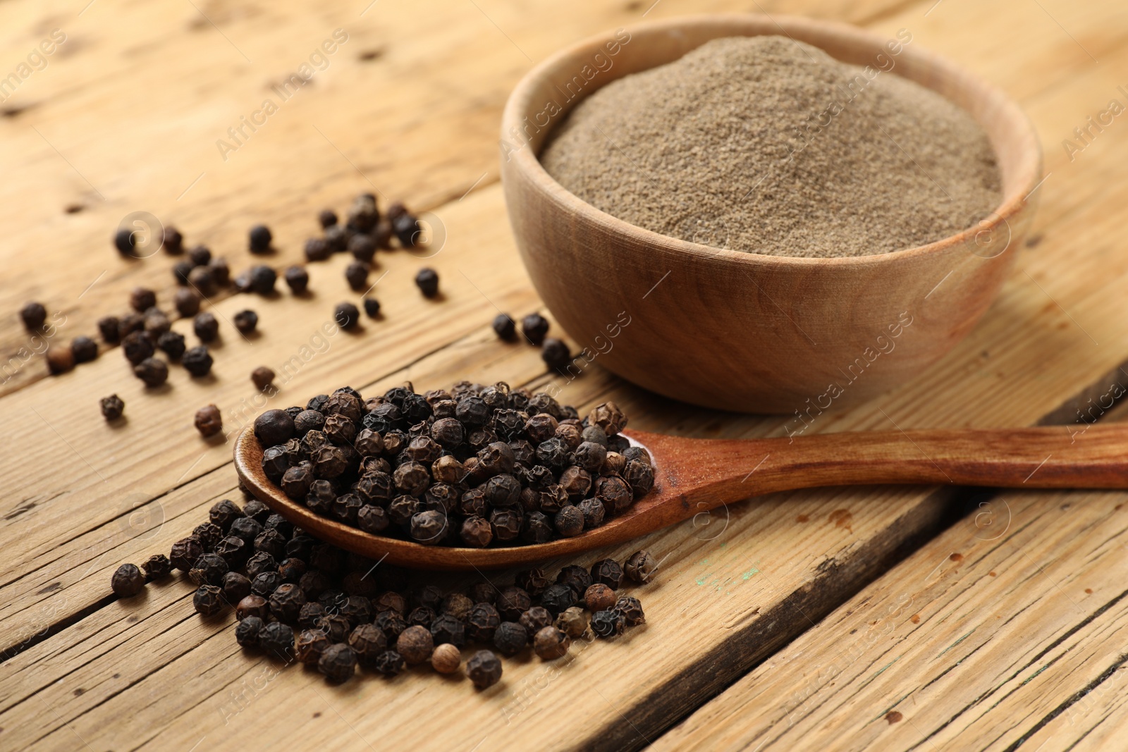 Photo of Aromatic spice. Ground and whole black pepper on wooden table, closeup