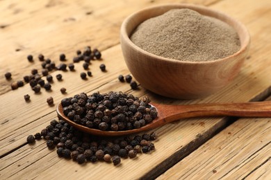 Photo of Aromatic spice. Ground and whole black pepper on wooden table, closeup