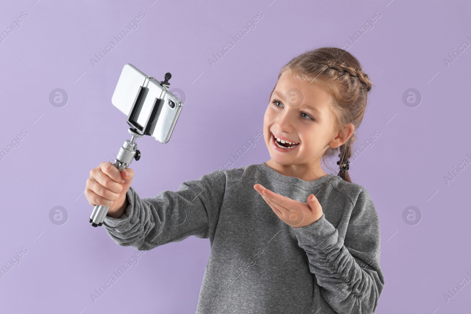 Photo of Cute little blogger recording video on violet background