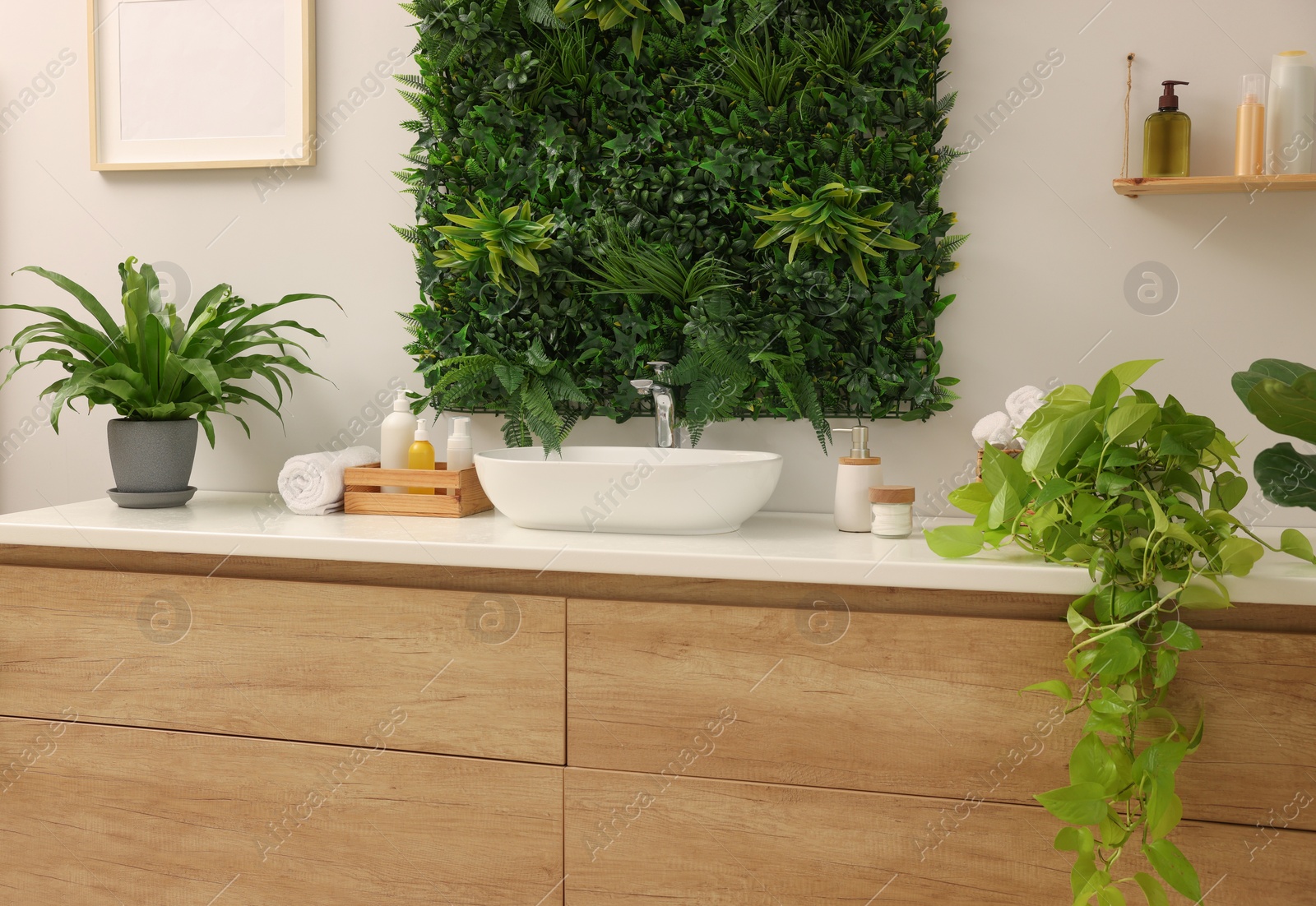 Photo of Green artificial plants, vanity and different personal care products in bathroom