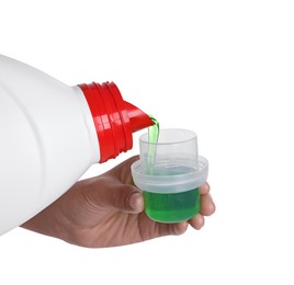 Photo of Woman pouring fabric softener from bottle into cap on white background, closeup