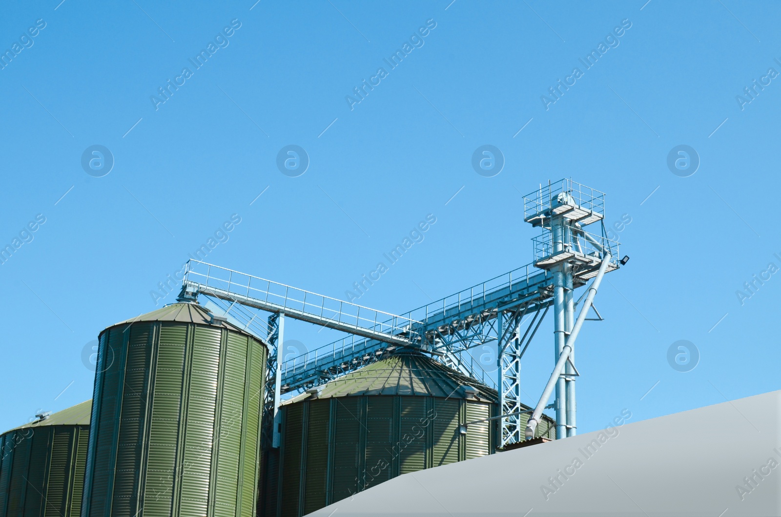 Photo of Modern granaries for storing cereal grains against blue sky, low angle view