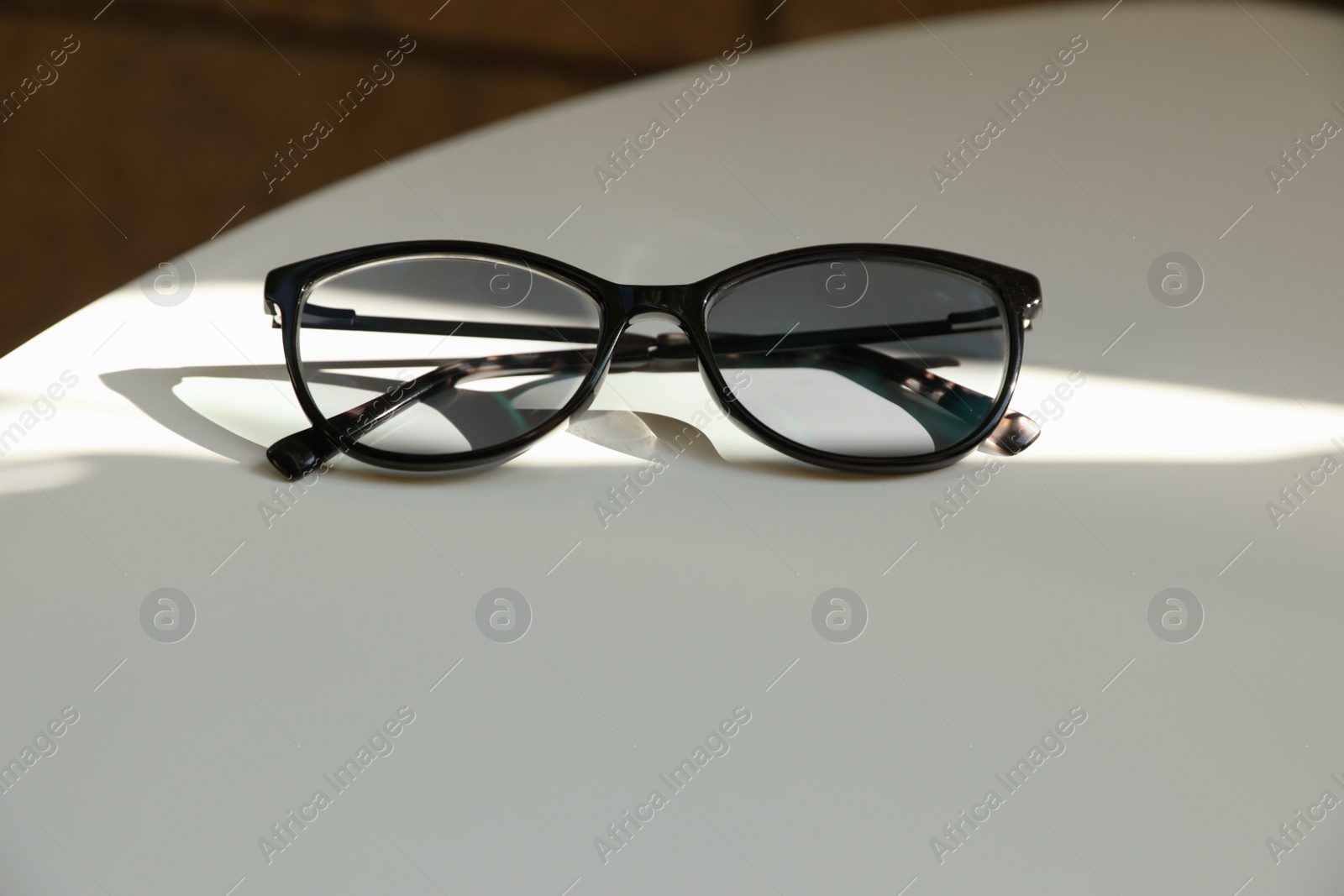 Photo of Stylish black eye glasses on white table. Space for text