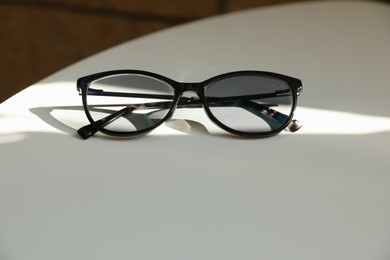 Stylish black eye glasses on white table. Space for text