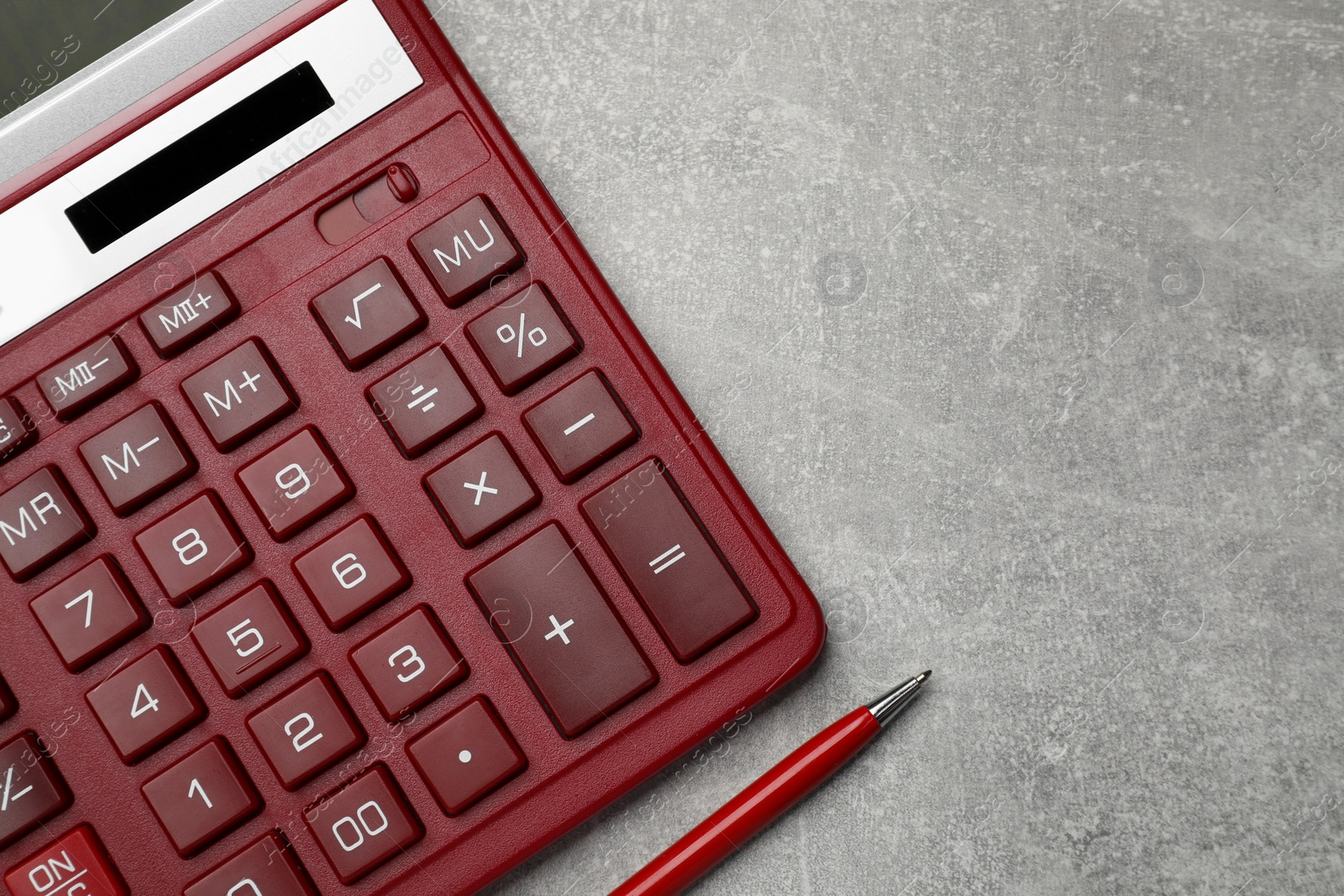 Photo of Calculator and pen on grey table, top view. Space for text