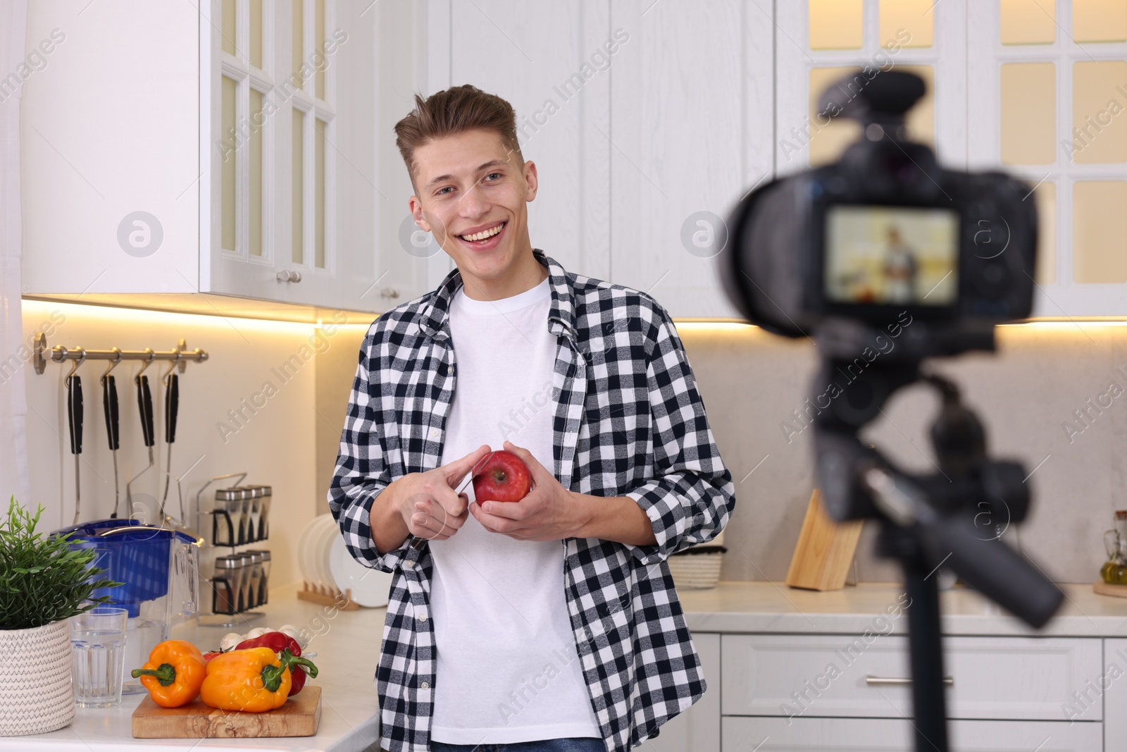 Photo of Smiling food blogger cooking while recording video in kitchen