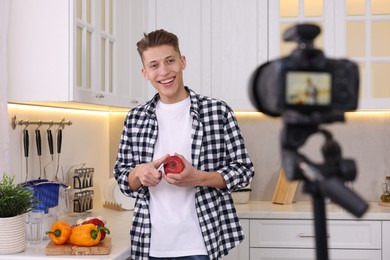 Smiling food blogger cooking while recording video in kitchen