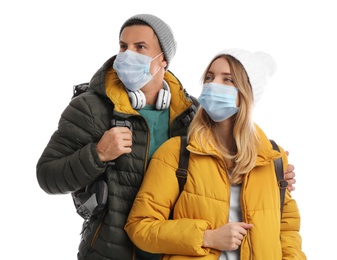 Photo of Couple in face masks and warm clothes on white background. Winter travel