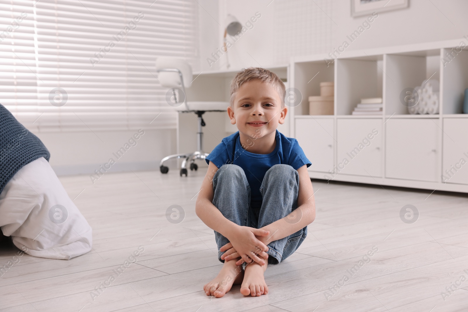 Photo of Cute little boy sitting on warm floor at home. Heating system