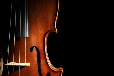 Photo of Classic violin on black background, closeup. Space for text