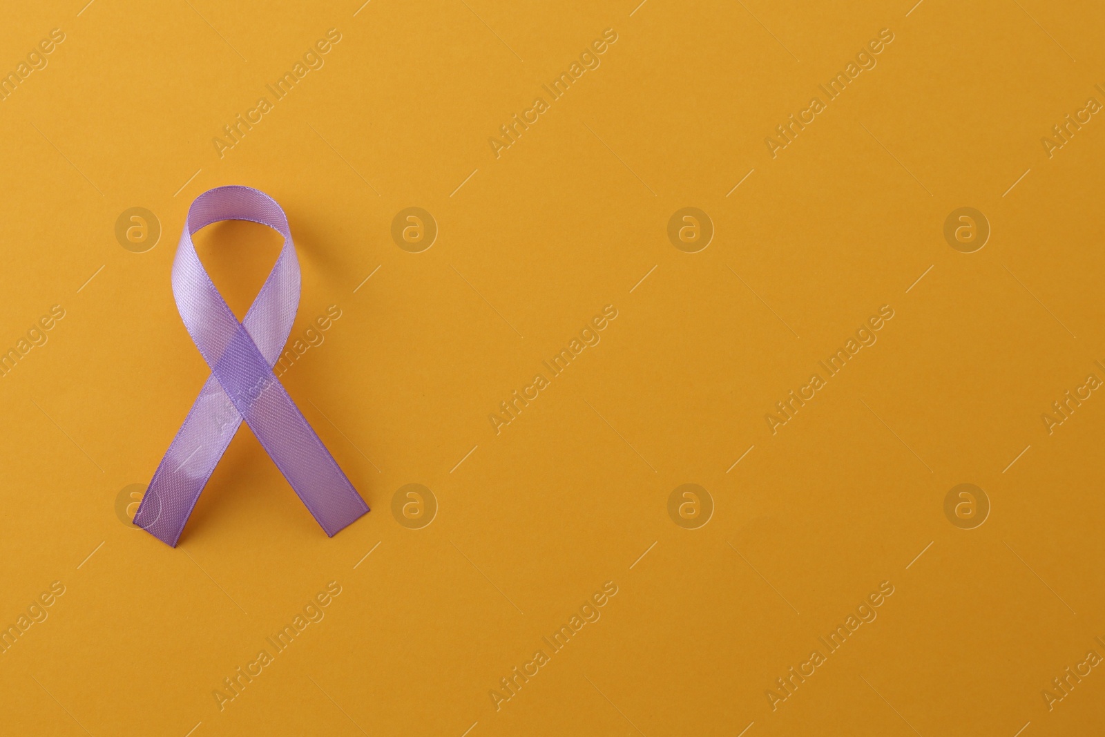 Photo of Violet awareness ribbon on orange background, top view. Space for text