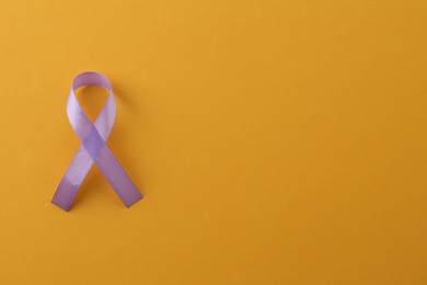 Violet awareness ribbon on orange background, top view. Space for text