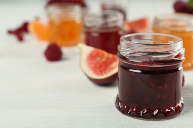 Open glass jar of sweet jam on white wooden table, closeup. Space for text