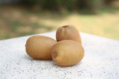 Photo of Whole fresh kiwis on white table with pattern outdoors