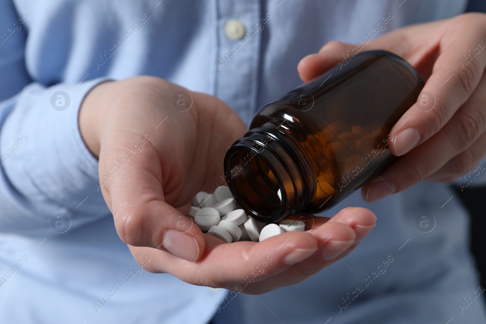 Photo of Woman pouring pills from bottle, closeup view