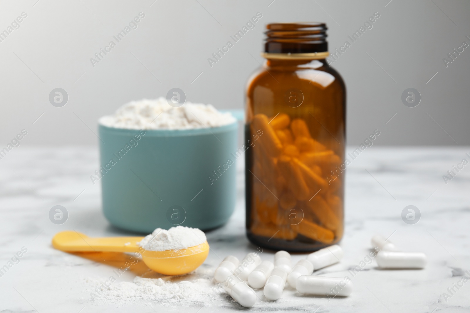 Photo of Amino acid pills and powder on white marble table