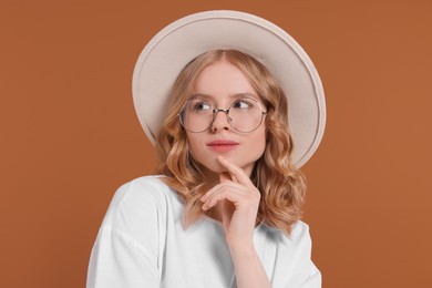 Beautiful woman with blonde hair in hat on brown background