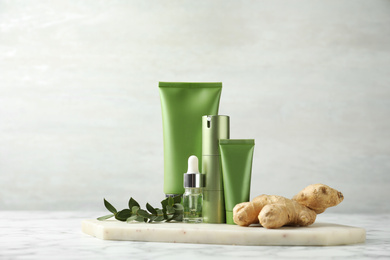Photo of Set of cosmetic products, ginger and plant on white marble table