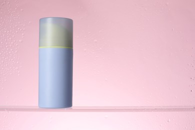 Photo of Bottle with moisturizing cream on pink background, view through wet glass