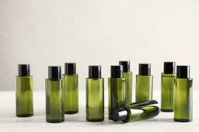 Mini bottles with cosmetic products on white wooden table