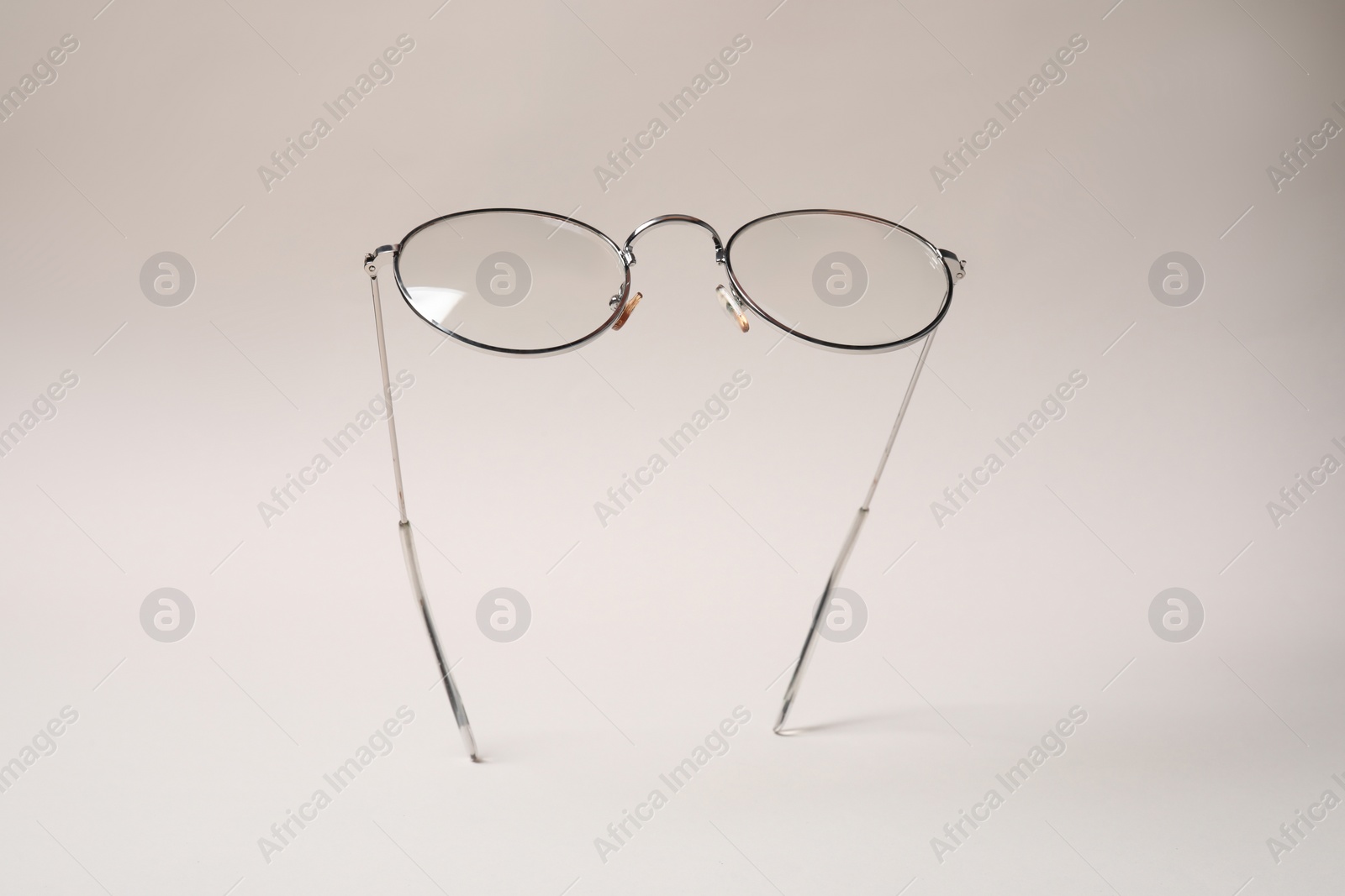 Photo of Stylish pair of glasses with metal frame on beige background