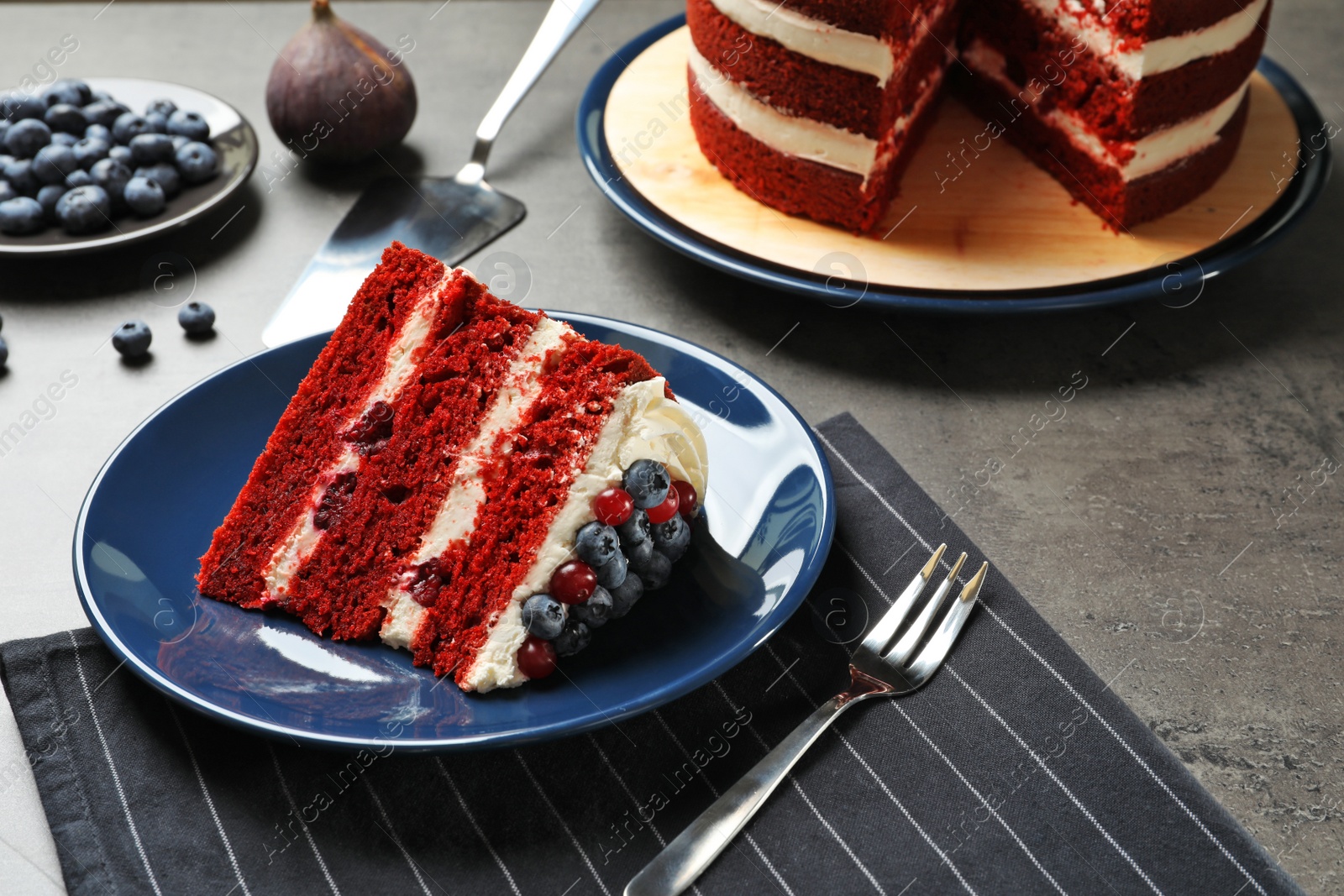 Photo of Plate with piece of delicious homemade red velvet cake on table