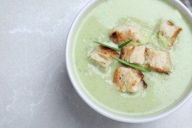 Photo of Bowl of delicious asparagus soup on light grey table, top view. Space for text