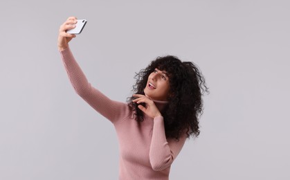 Photo of Beautiful young woman taking selfie on light grey background