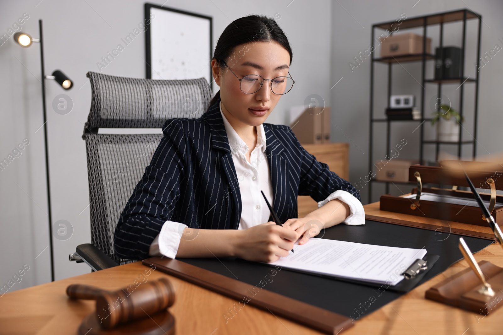 Photo of Notary signing document at table in office