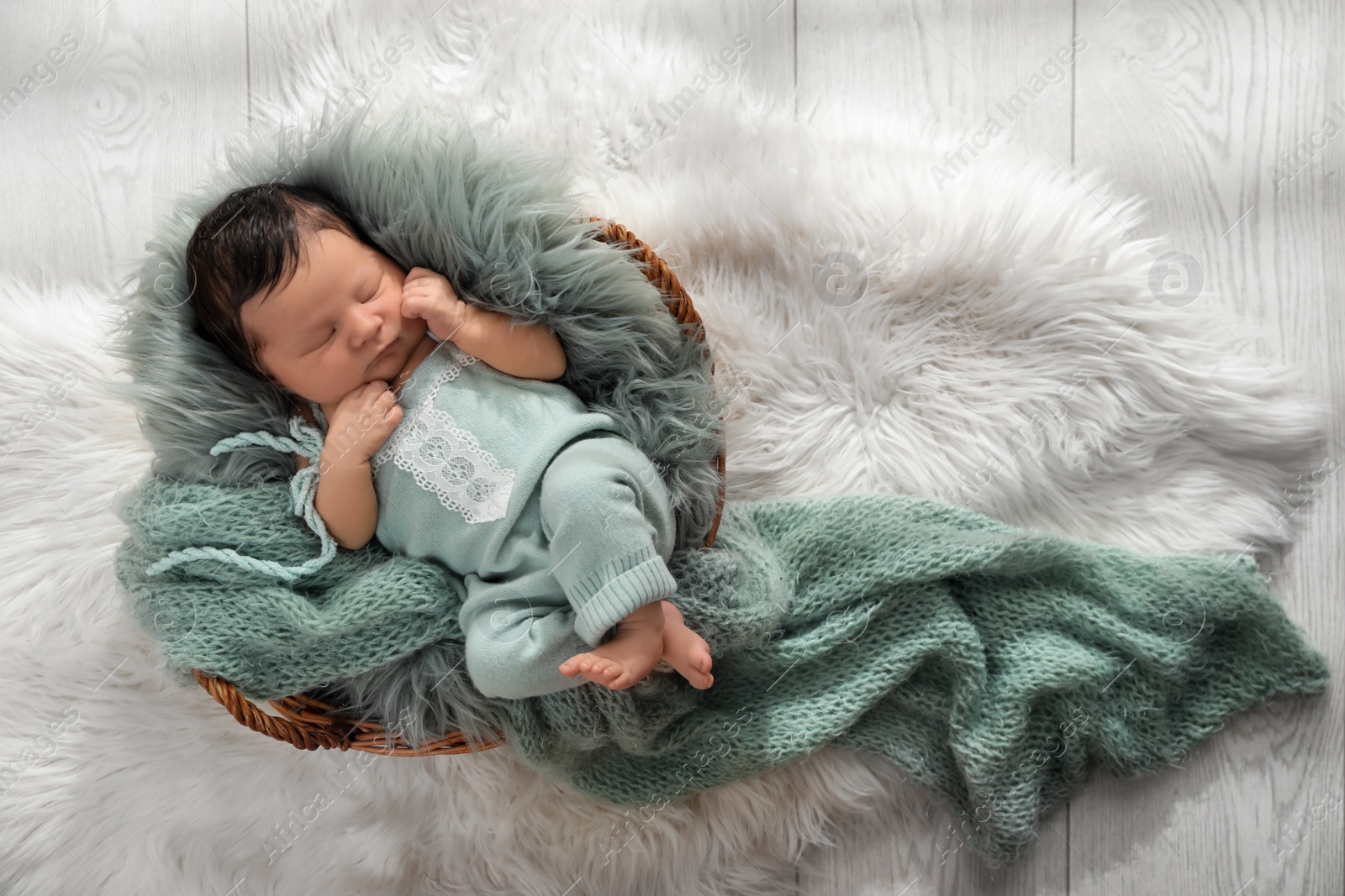 Photo of Cute newborn baby sleeping in wicker basket, top view