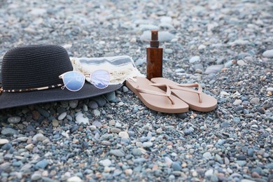 Photo of Set of different stylish beach accessories on pebble seashore