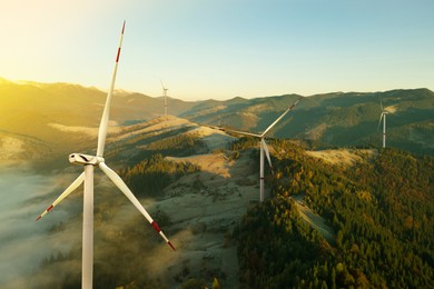 Image of Modern wind turbines in mountains on sunny day. Alternative energy source