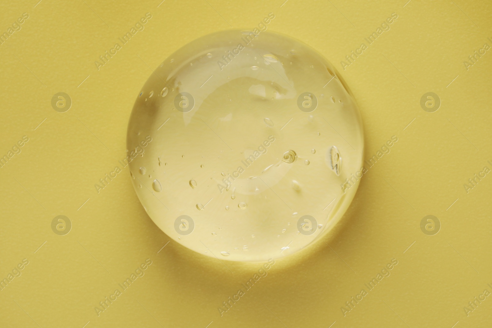 Photo of Sample of clear cosmetic gel on yellow background, top view