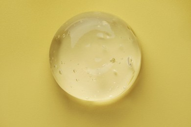 Sample of clear cosmetic gel on yellow background, top view