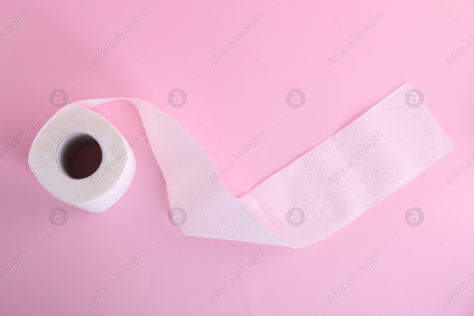 Photo of Soft toilet paper roll on pink background, top view