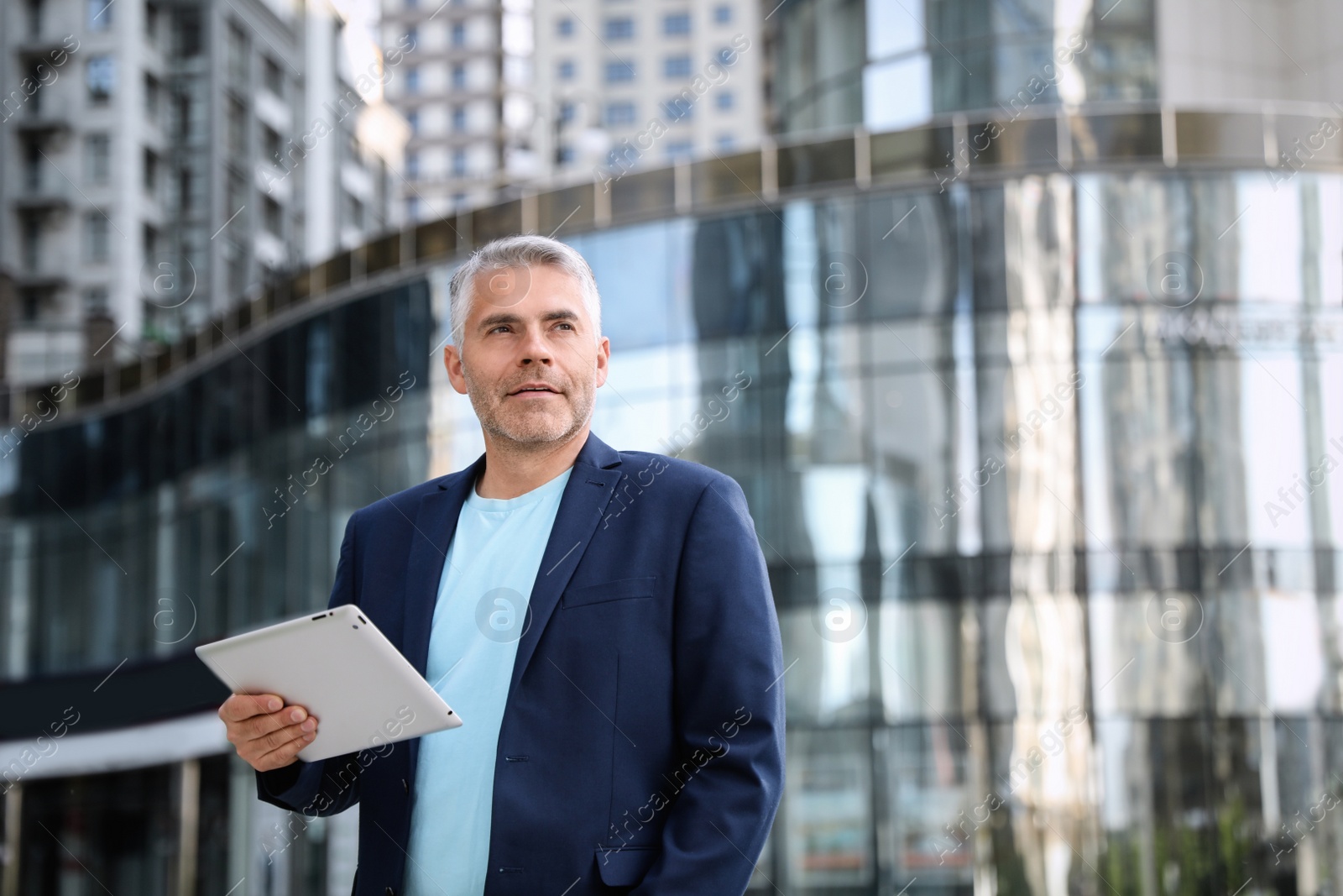 Photo of Portrait of handsome mature man with tablet in city center. Space for text