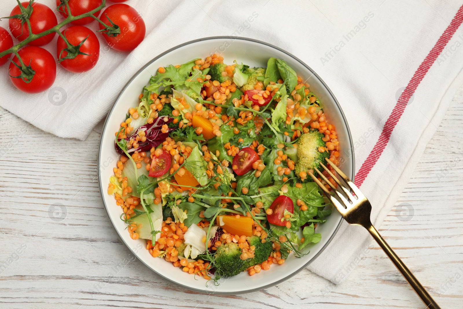 Photo of Delicious salad with lentils and vegetables served on white wooden table, flat lay