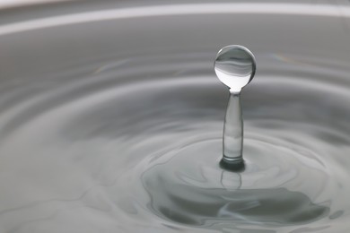 Photo of Splash of clear water with drop on light grey background, closeup. Space for text