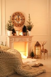 Photo of Beautiful room interior with decorative fireplace and potted fir trees. Christmas decor