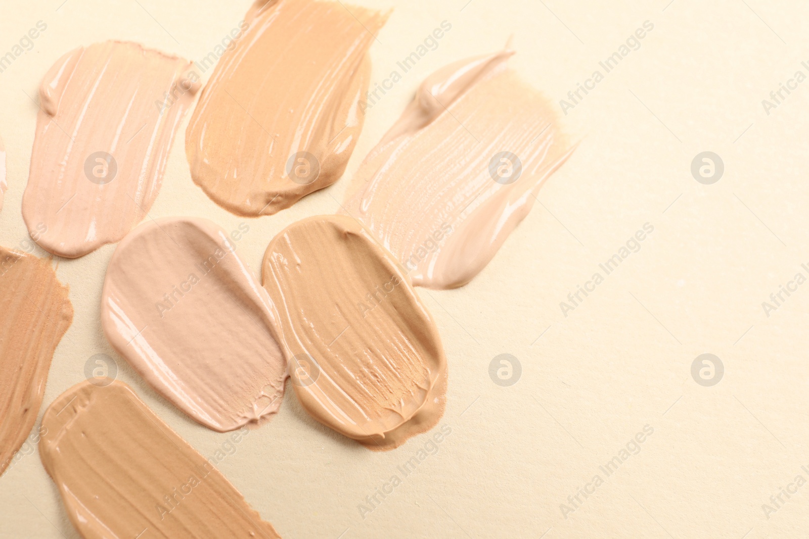 Photo of Samples of skin foundation on beige background, closeup. Space for text