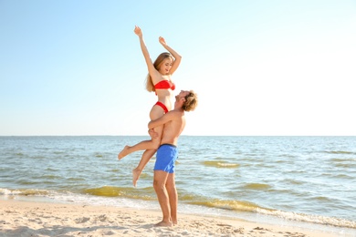 Photo of Happy young couple in beachwear having fun on seashore