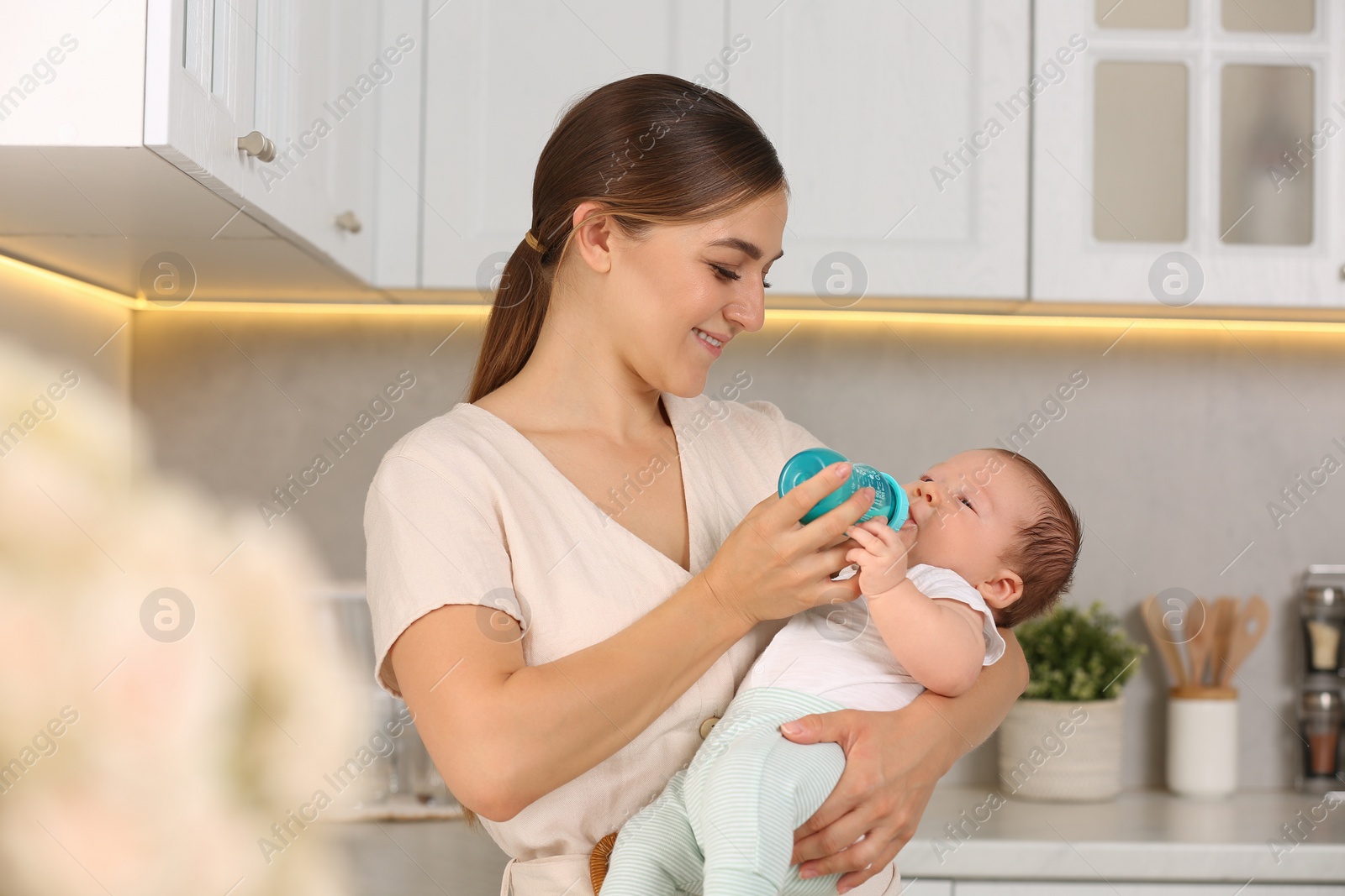 Photo of Mother feeding her cute child with infant formula indoors