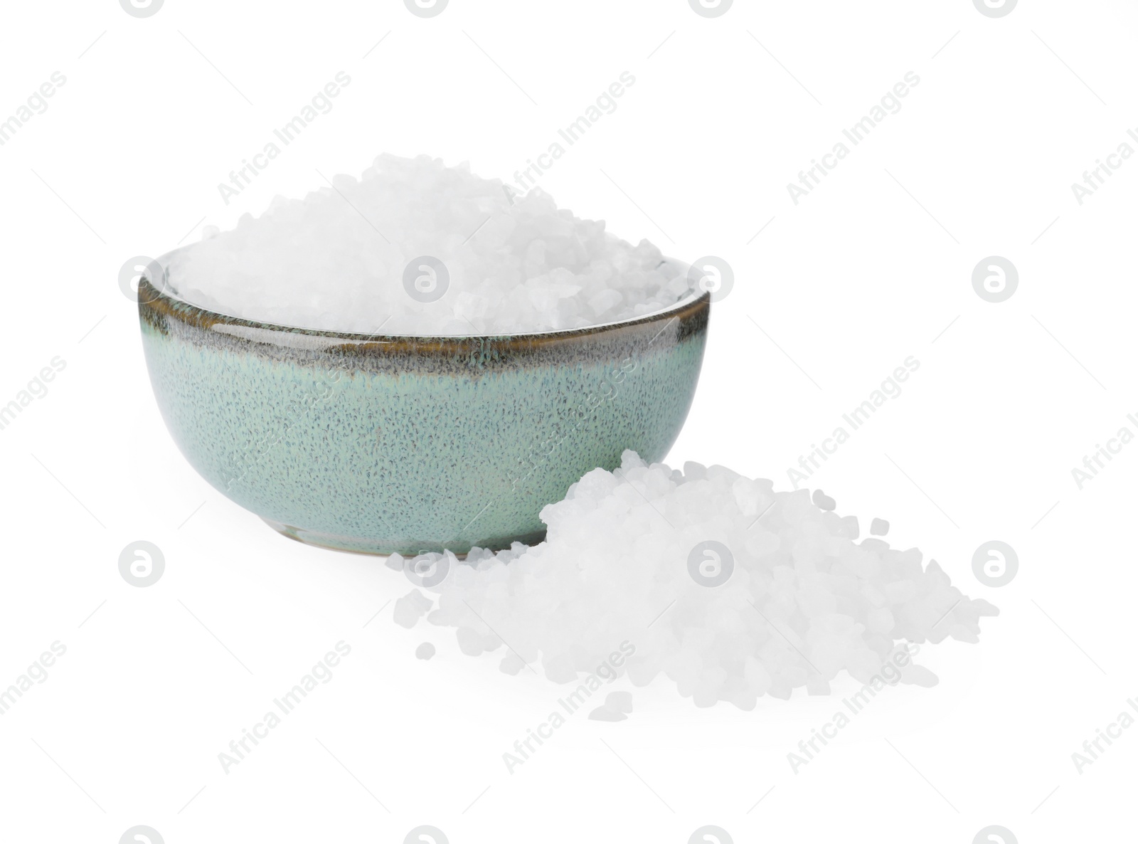 Photo of Ceramic bowl and heap of natural sea salt isolated on white