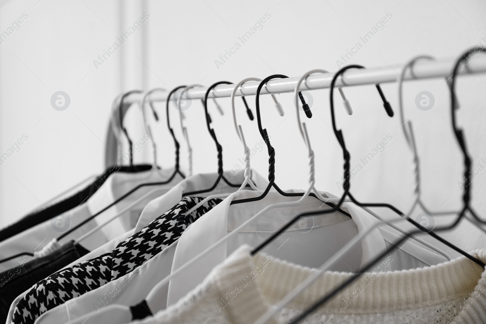 Photo of Rack with stylish clothes near white wall, closeup