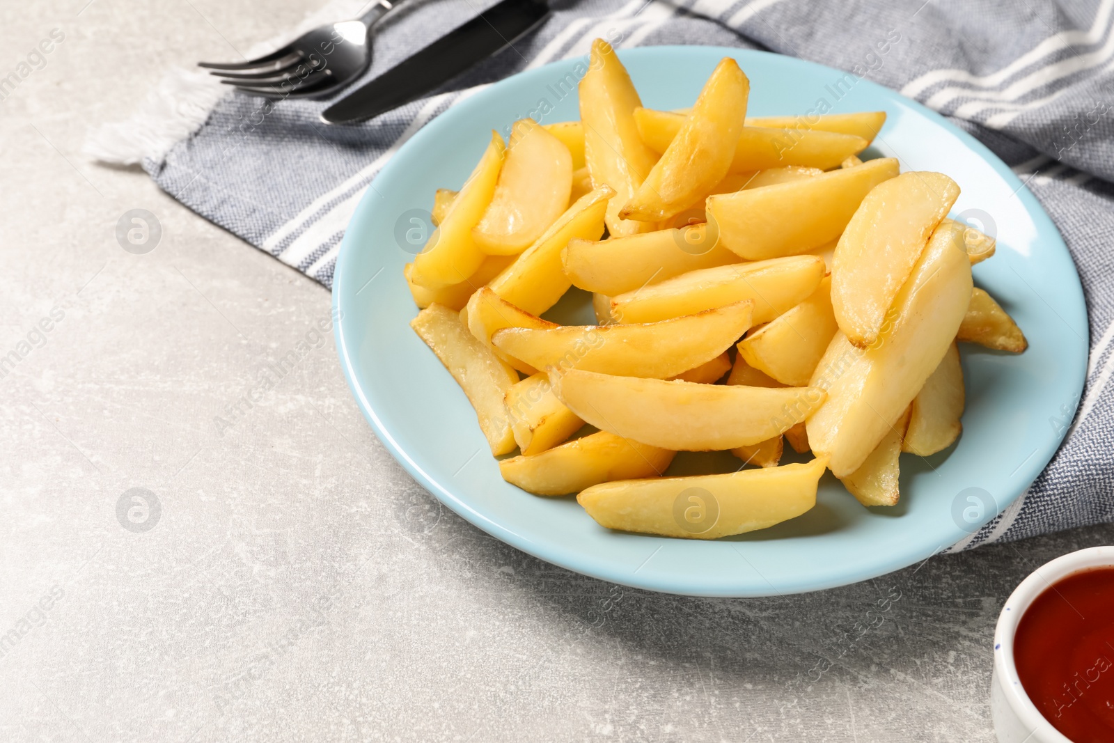 Photo of Plate with tasty baked potato wedges and sauce on grey table